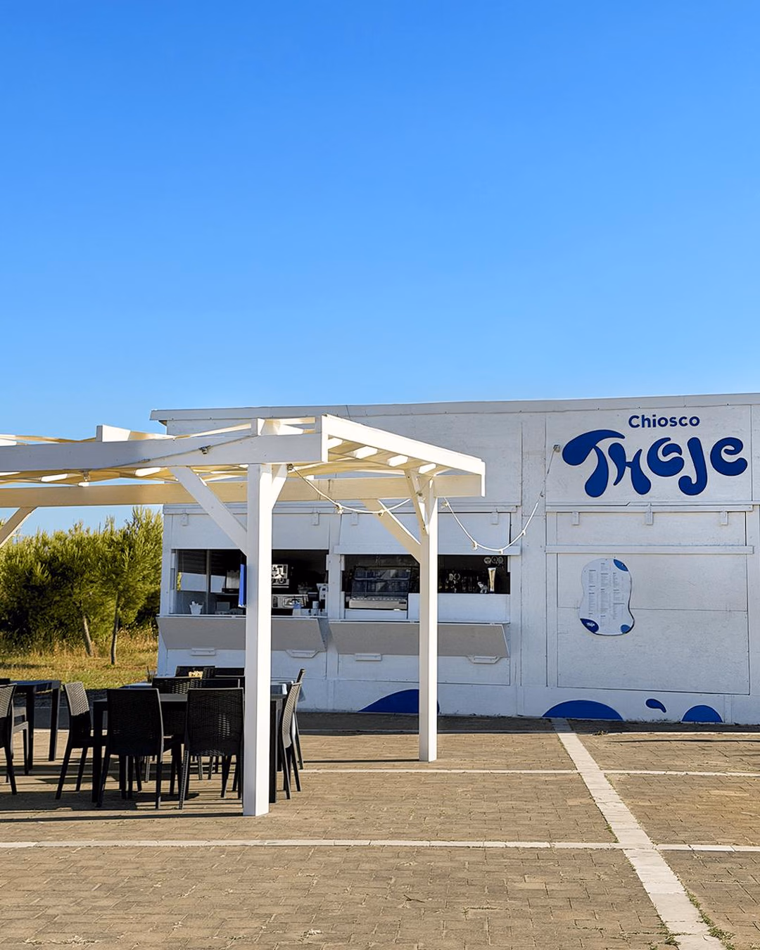 Insegna del Chiosco Thoje dipinta in blu sulla facciata bianca del chiosco